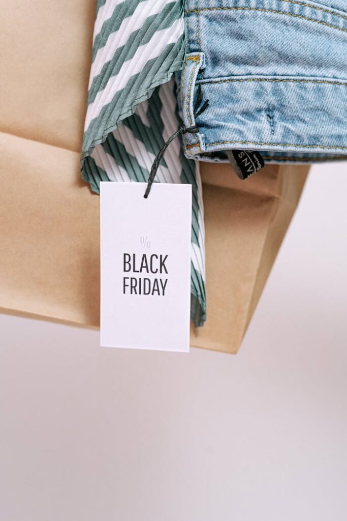 A Black Friday sale tag on a paper bag with denim clothing, symbolizing shopping discounts.